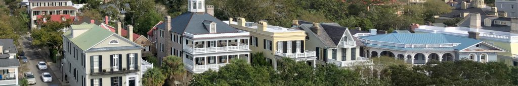 A panoramic view of homes on South Battery Street from the vantage point of above White Point Garden with a row of large homes of many colors.