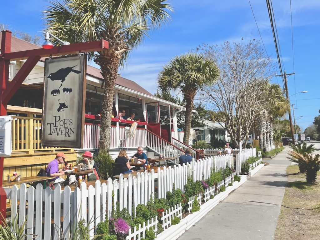 A sidewalk lined by a short white picket fence in front of the Poe's Tavern restaurant on Middle Street on Sullivan's Island.