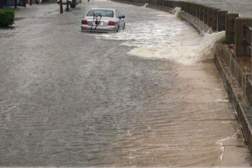 The Low Battery becoming inundated with overflowing seawater during a hurricane, with seawater flooding the street with an abandoned car.